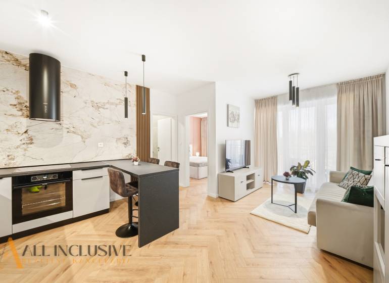 Living room and kitchen in a 4-room apartment with a wooden decor floor and light decoration.