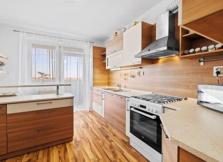 A kitchen in a 2-room apartment with a wooden decor kitchen unit and flooring.