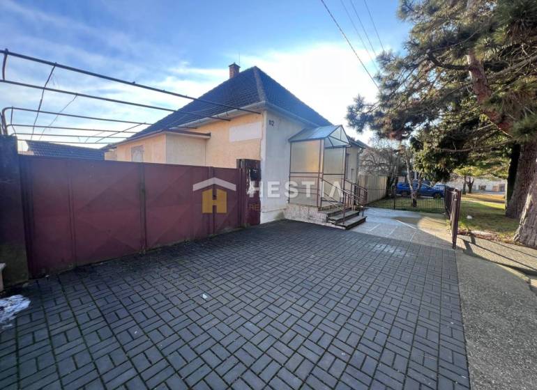 Family house with a garden in Senica, large entrance gate, paved courtyard, tree.