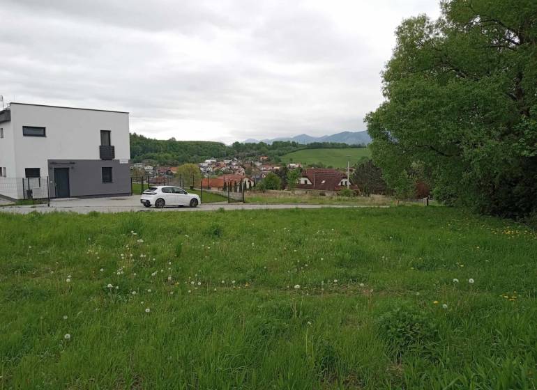 Plots - housing in Žilina on Chotárna show a green meadow with a modern building and a car.