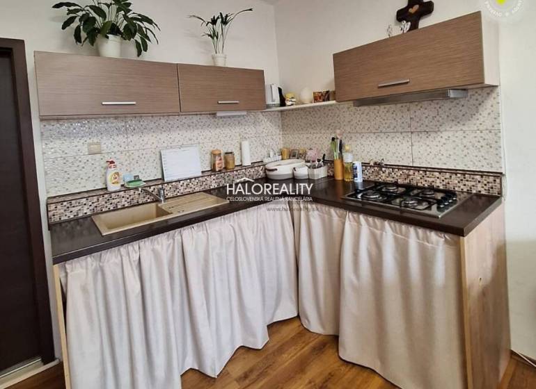 A kitchen in a 3-room apartment with a wooden decor floor and a gas stove.