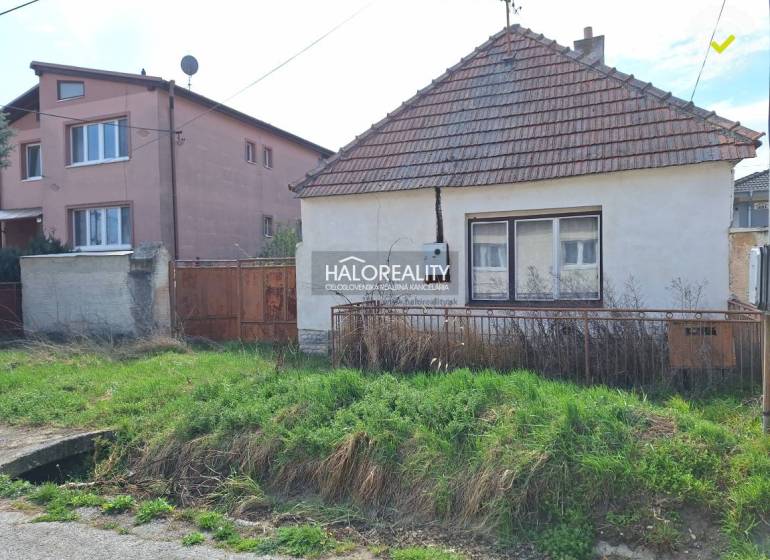 A house on a residential plot in the village of Dvorníky with a grassy garden and a fence.