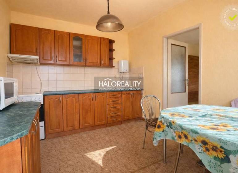 A kitchen in a family house with built-in cabinets and a table with a floral tablecloth.