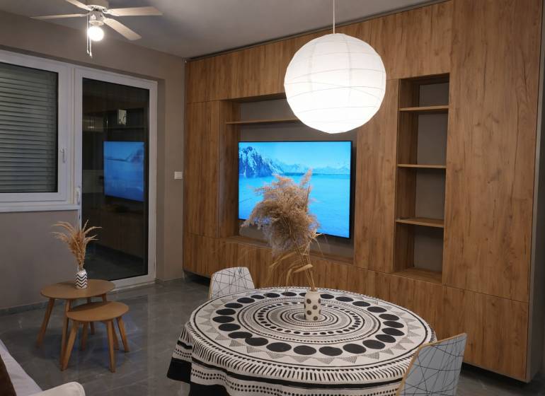 Living room in a two-room apartment with a wooden decor floor and a round table.
