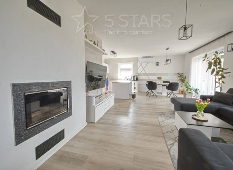 Living room with a fireplace, TV, and wood-patterned flooring in a family house.