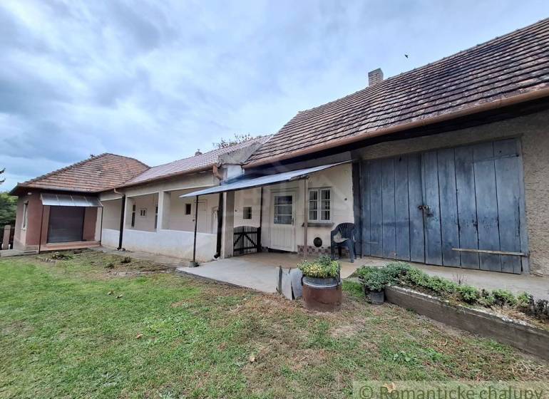 A family house in Mužla with a traditional facade, a veranda, and a lush garden.