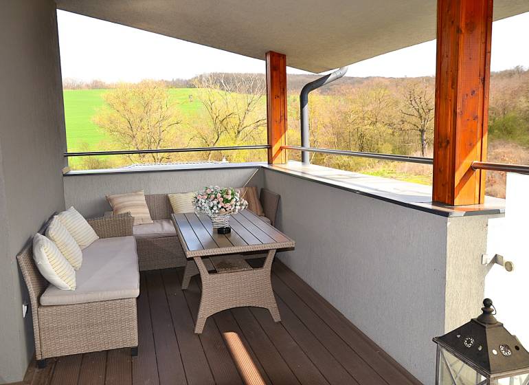 A spacious balcony with rattan furniture and a wooden decor floor in a studio apartment.
