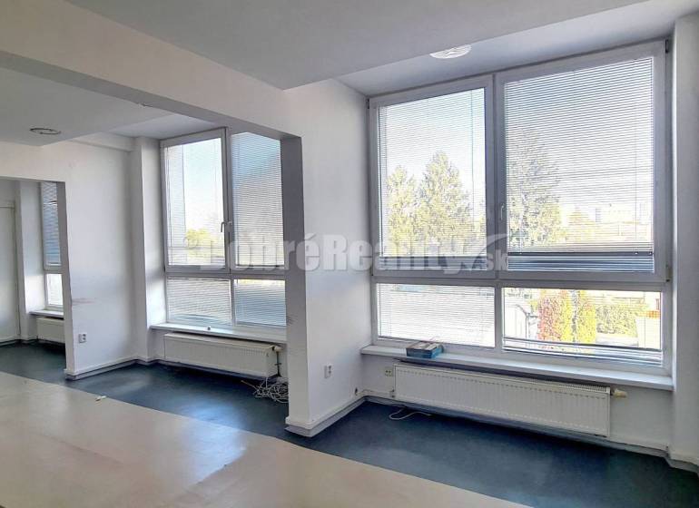 A spacious office with large windows and a wooden decor floor.