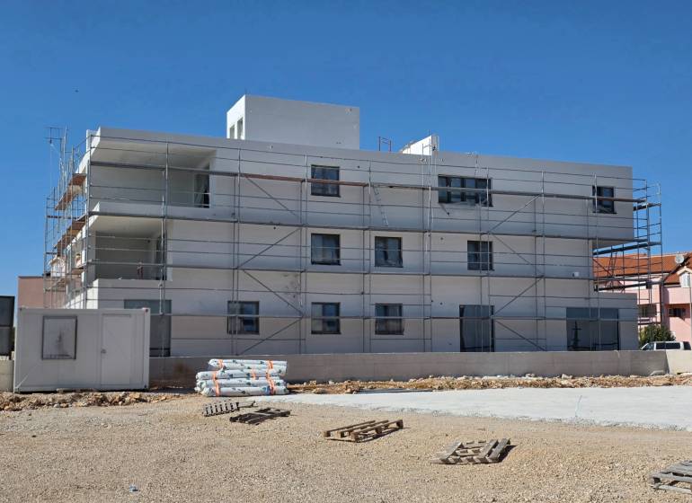 A building in the city of SRIMA with scaffolding and mess on the ground.