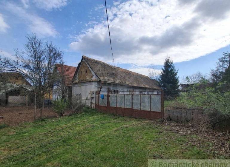 A family house in Ozdín, surrounded by a garden and trees, under a blue sky.