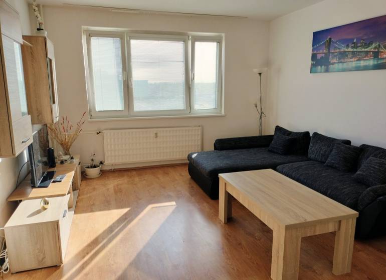Living room with a sofa, coffee table, and wood-patterned flooring in a 3-room apartment.