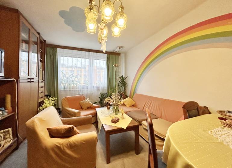 Living room in a 3-room apartment with a rainbow on the wall, comfortable sofas, and a table.
