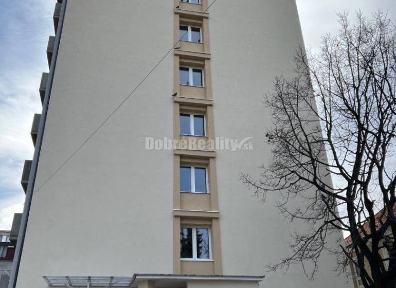 Apartment building in Prievidza on T. Vansovej Street, where an orange car is parked.
