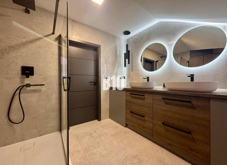 A bathroom in a 4-room apartment with two oval mirrors and a shower corner.