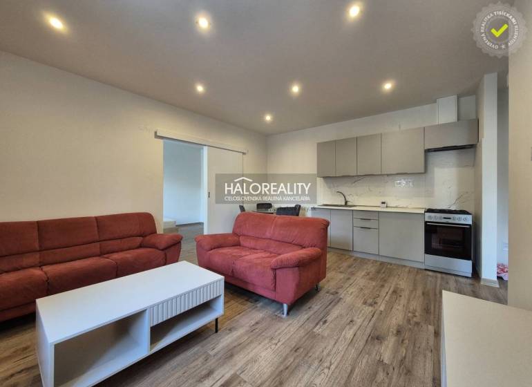 Living room in a two-room apartment with a wooden decor floor, red sofas, kitchen.