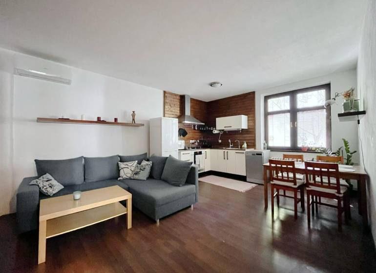 Living room with kitchen in a two-room apartment with a wooden decor floor.