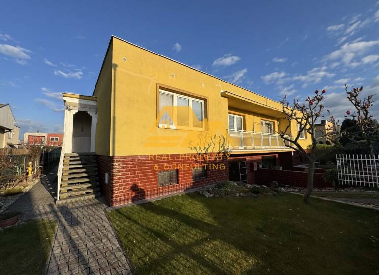 Yellow family house in Nové Zámky on a street with a landscaped garden and walkway.