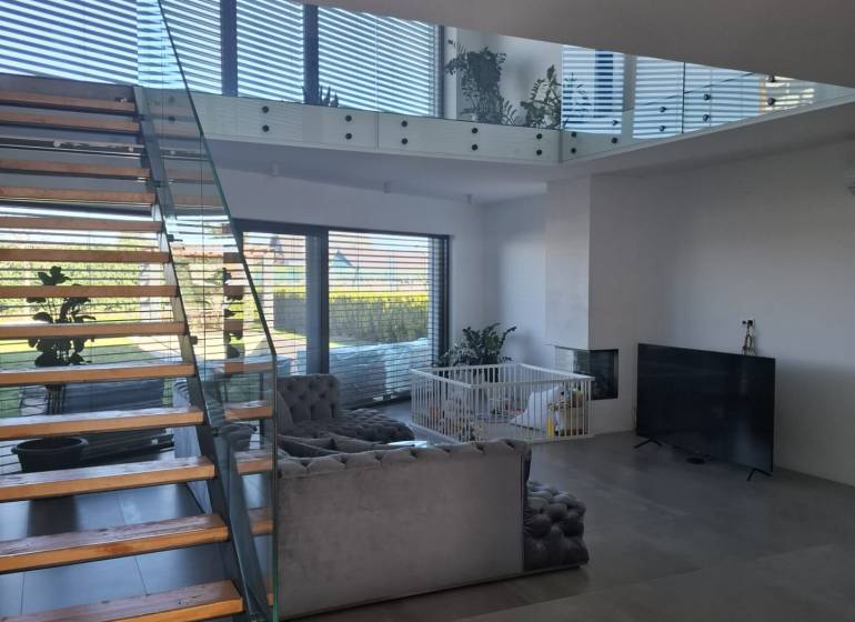 Living room in a family house with a staircase and glass railings.