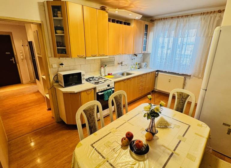 A kitchen in a 3-room apartment with a wooden decor floor and a dining table.