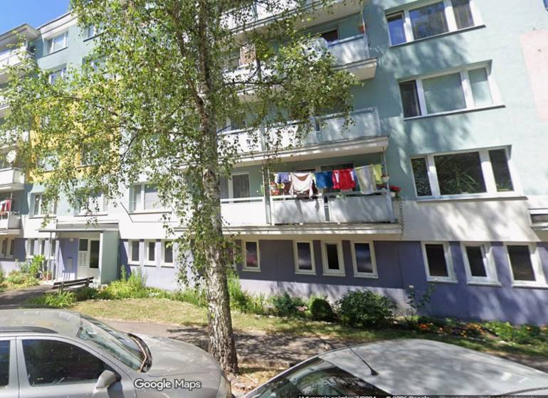 Apartment building on Beskydská 9 in Banská Bystrica with greenery and a woman in the front.