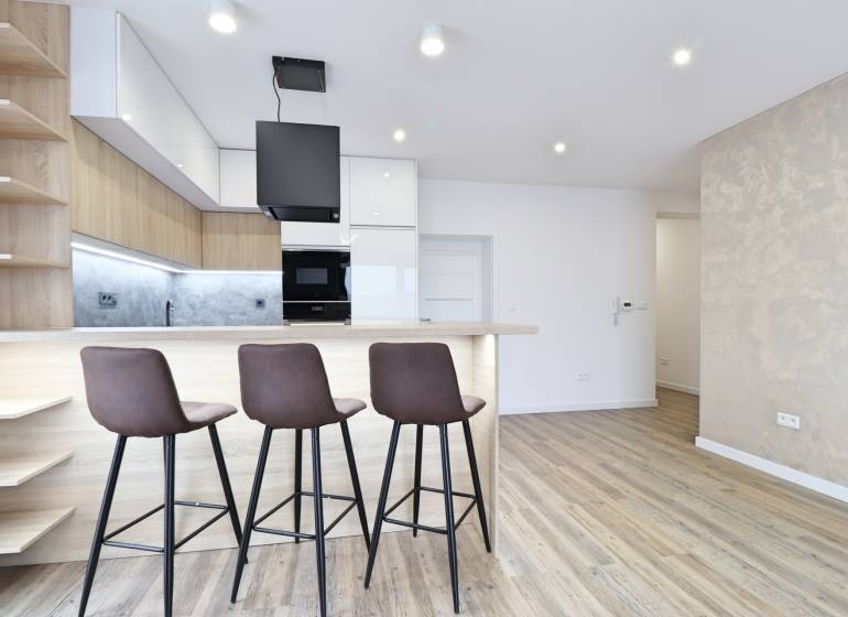 A kitchen with a bar counter and a wooden decor floor in a 3-room apartment.