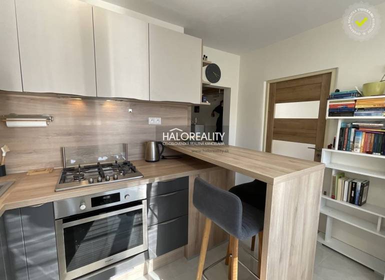 A kitchen in a studio apartment with a kitchen counter and appliances.