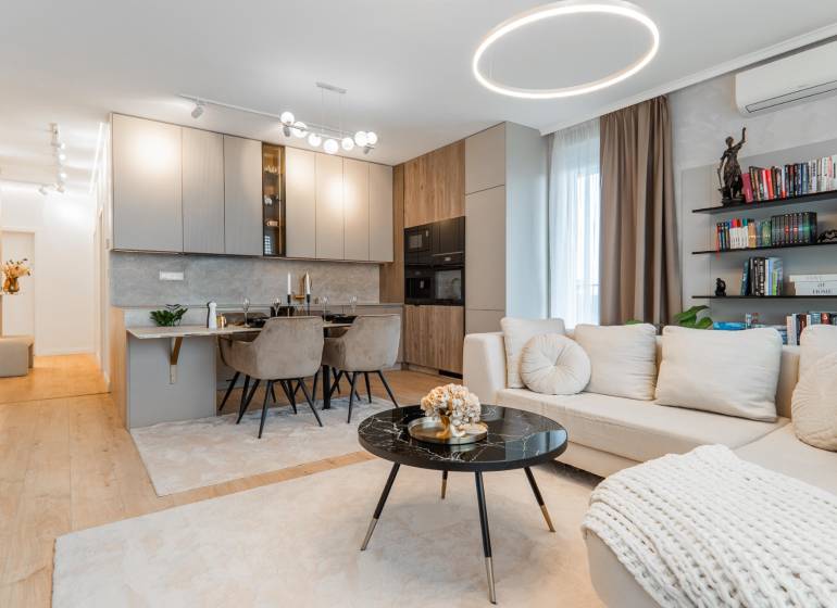A stylish living room with a kitchen in a 3-room apartment, light shades, wooden decor flooring.