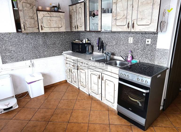 A kitchen with tiles and a kitchen unit in a 2-room apartment.