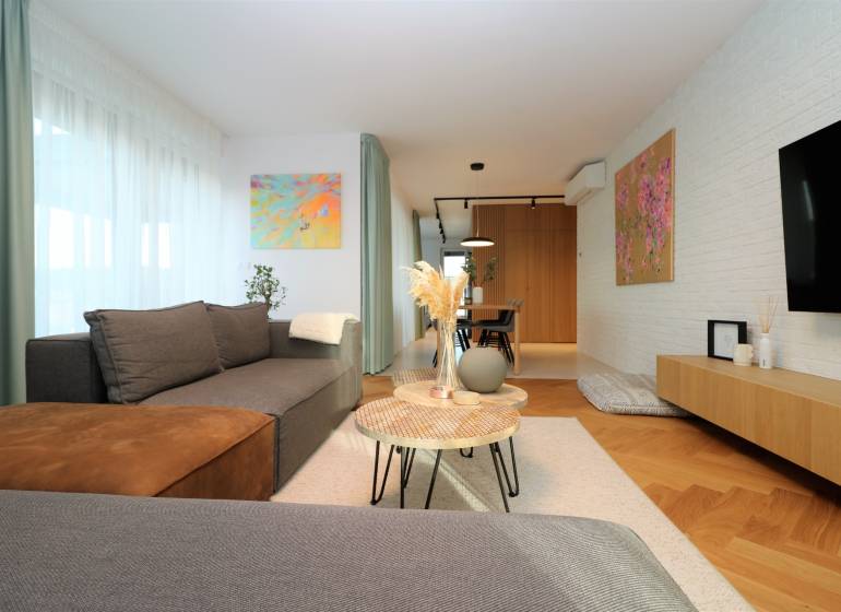 A stylish living room in a 4-room apartment with a wood-patterned floor and artistic paintings.