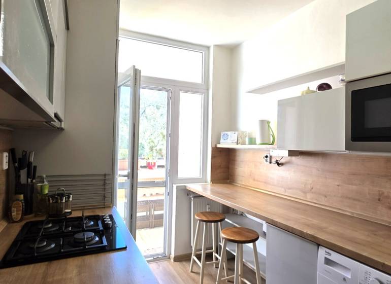 A kitchen in a 3-room apartment with a bar counter, microwave, and cooktop.