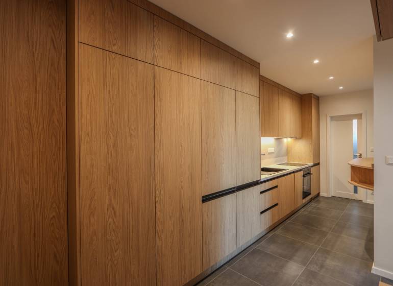 A kitchen in a 3-room apartment with a wood-patterned floor and built-in appliances.