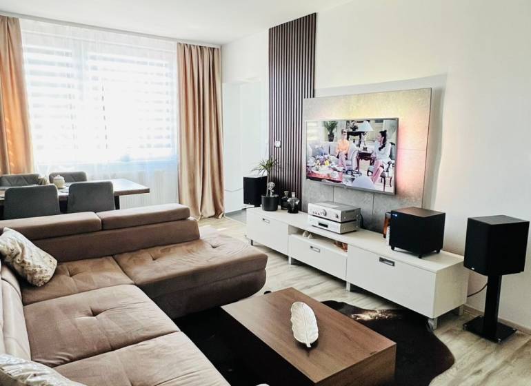 Living room with a corner sofa, TV stand, and wooden decor flooring.