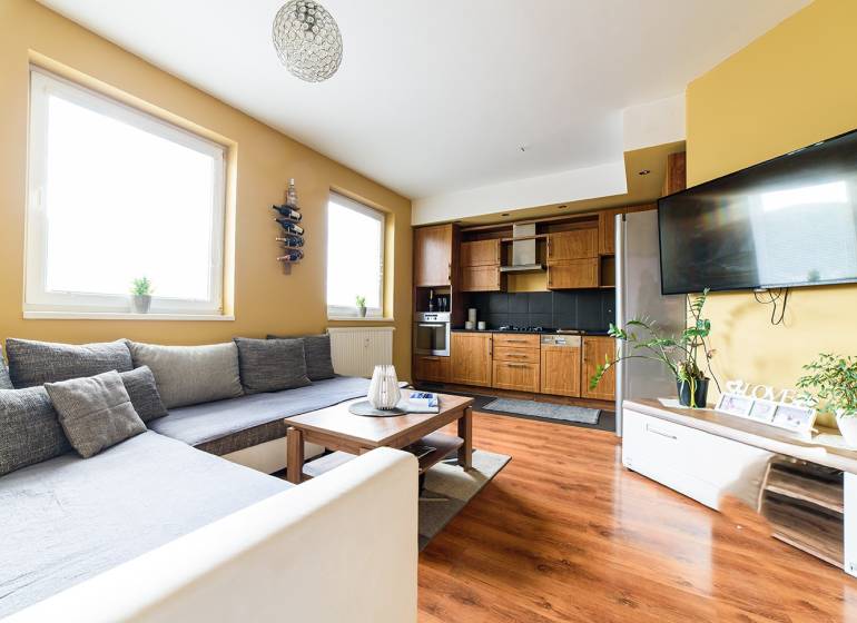 Living room in a 2-room apartment with a kitchenette and a floor with a wooden decor.