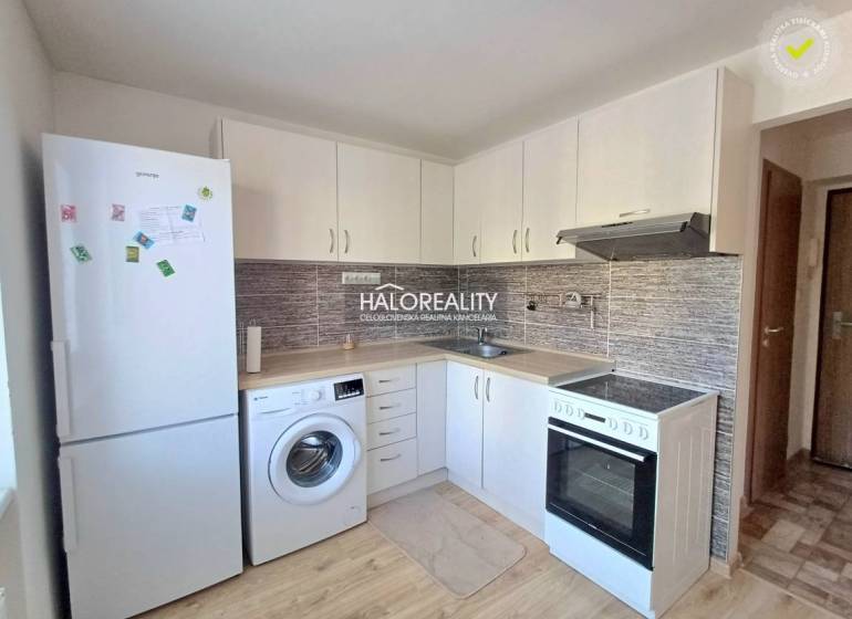 A kitchen in a studio apartment with white cabinets and a wood-patterned floor.