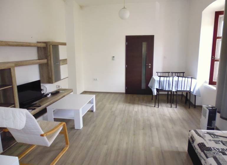 Living room in a three-room apartment with light furniture and a wooden decor floor.