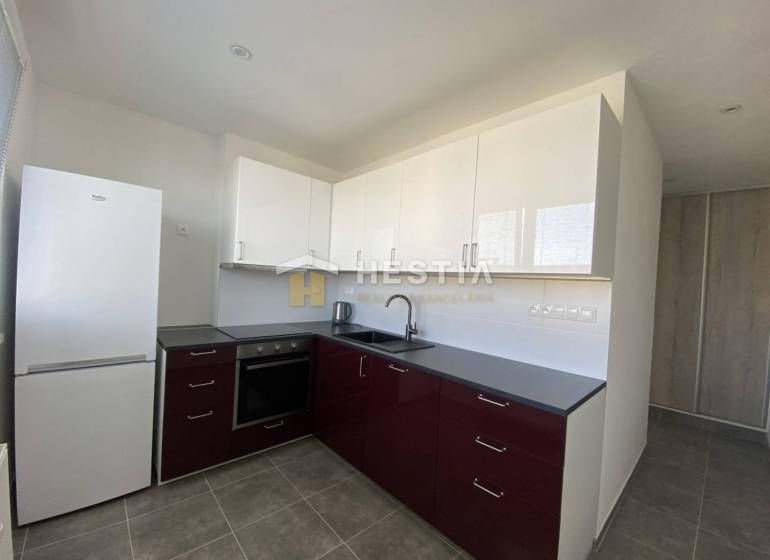 A kitchen in a 2-room apartment with dark cabinets and white appliances.