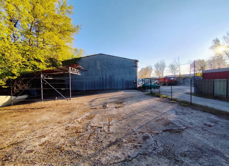 An industrial property with a parking lot surrounded by trees in Nitra, suitable for commercial use.