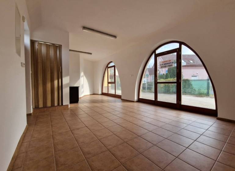 Interior of commercial spaces with large arched windows, tiled floor, and wooden doors.