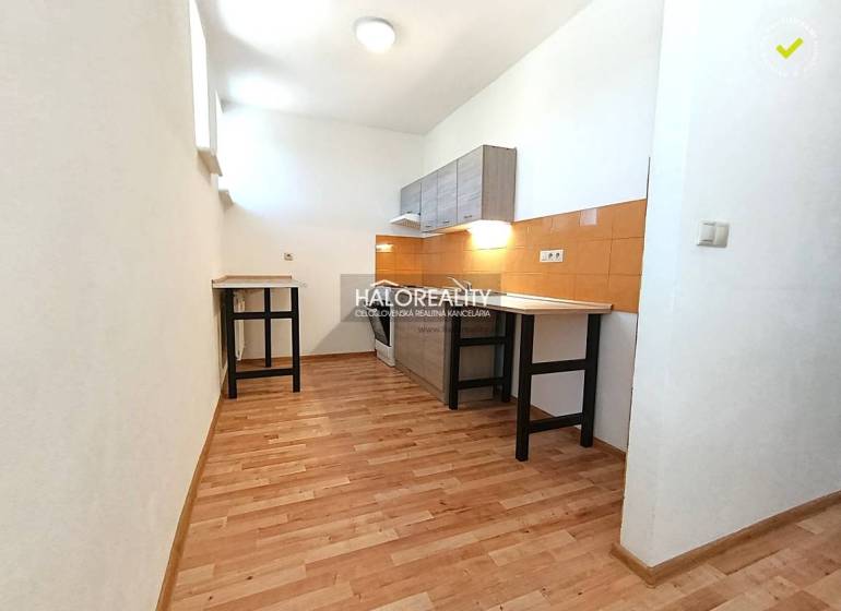 A kitchen in a 2-room apartment with a wooden decor floor and orange tiles.