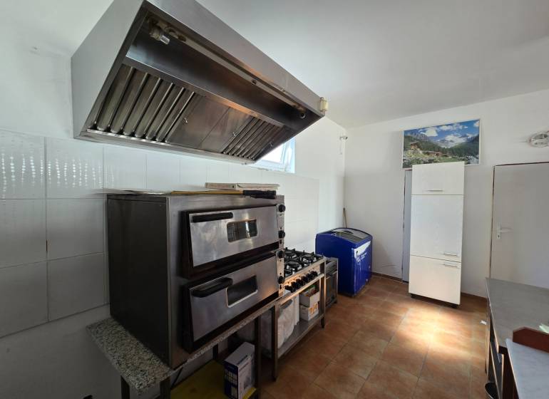 Gastro premises with an oven, extractor hood, and refrigerator, floor with wooden decor.