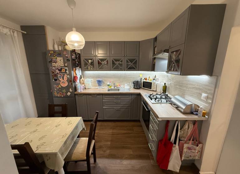 A kitchen in a 4-room apartment with a wooden decor floor and a corner kitchen unit.