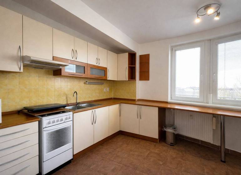 A kitchen in a 3-room apartment with white cabinets, yellow tiles, and a gas stove.