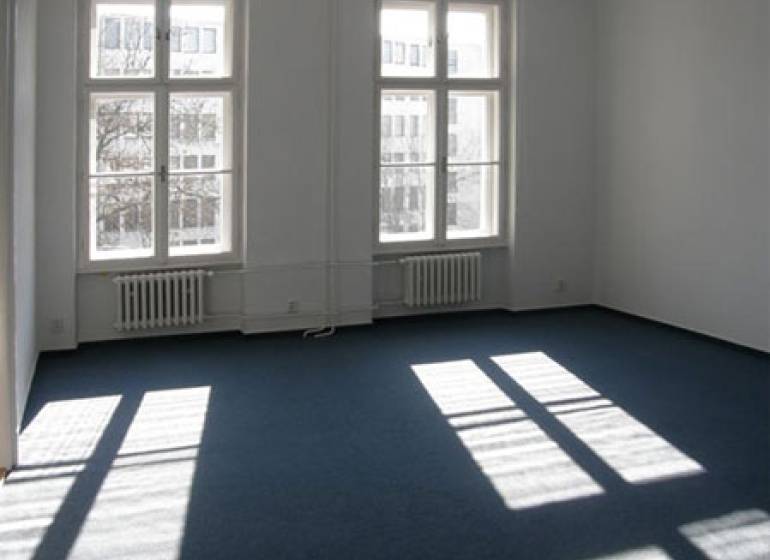 Offices with large windows and blue carpet.