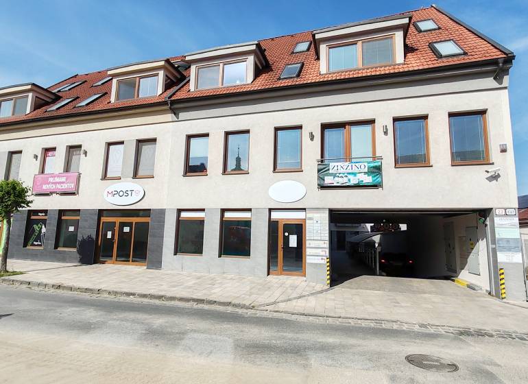 Commercial premises in Trnava with a white facade, red roof, and advertising signs.
