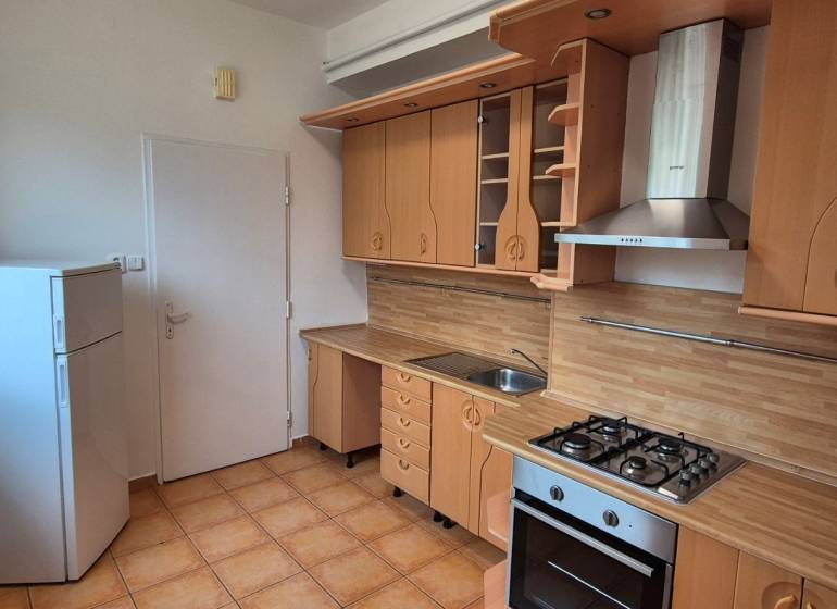 A kitchen in a 3-room apartment with a wooden decor kitchen unit and appliances.