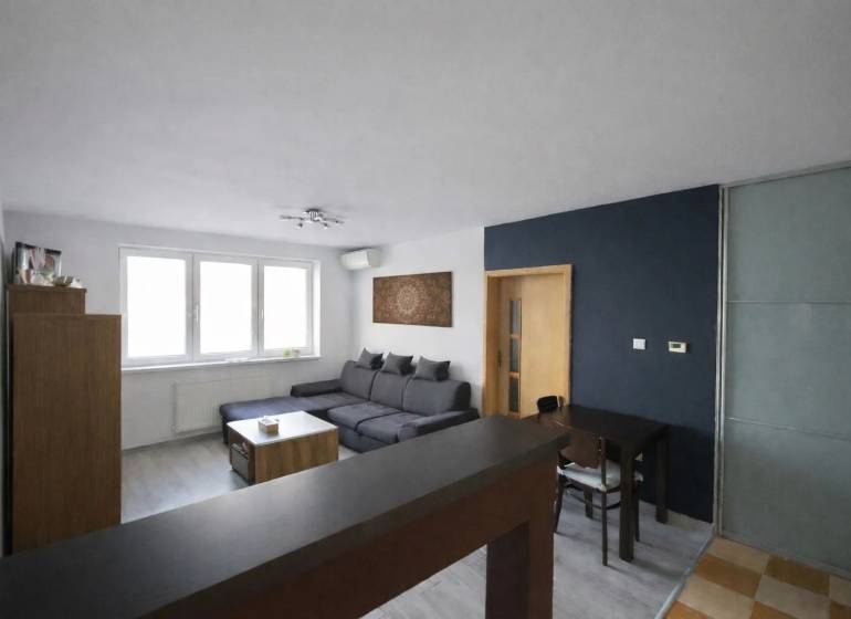 Living room in a three-room apartment with a corner sofa and a floor with a wooden decor.