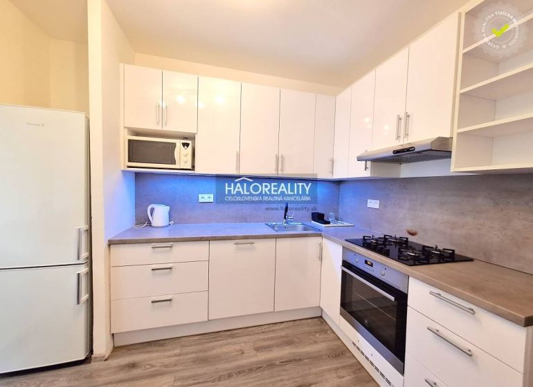 White kitchen in a 4-room apartment with wooden floor decor and modern appliances.