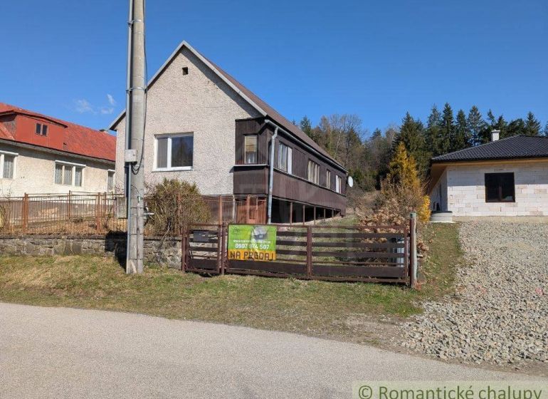 Family house in Kalinovo with wooden cladding, fence, and surrounding nature for sale.