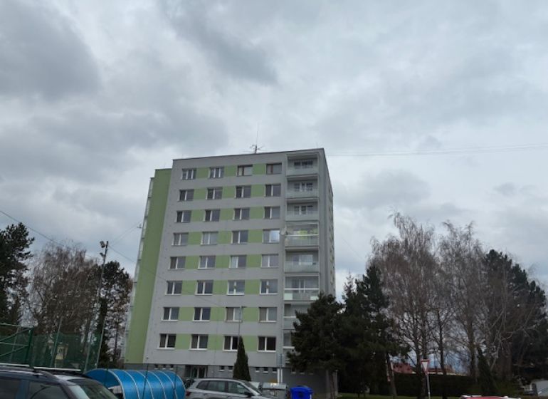 Apartment building on SNP Street in Ilava, surrounded by trees and parked cars.
