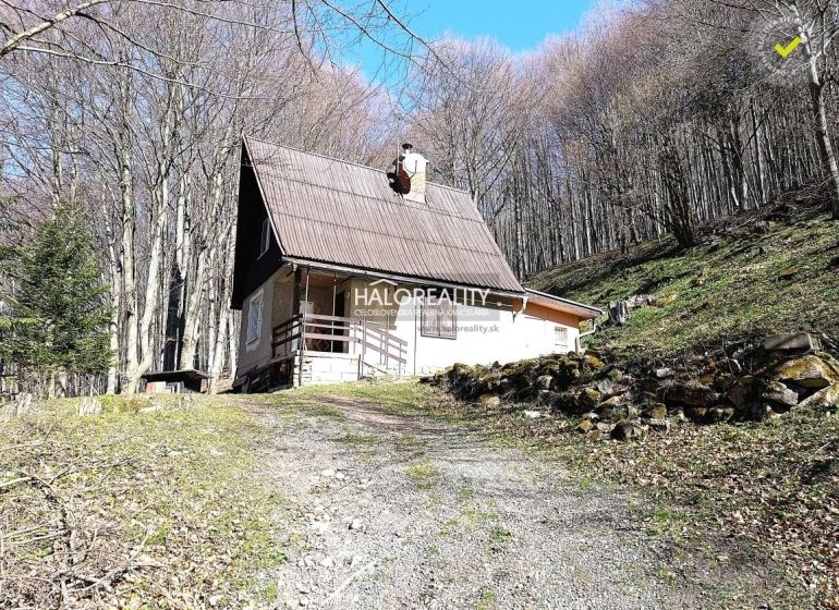 A cabin in Lehoty pod Vtáčnikom in the middle of the forest with a wooden terrace and a steep roof.